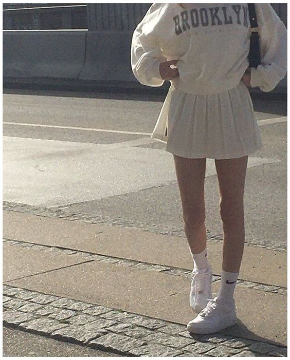 A girl wearing the latest fashion trends in a white tennis skirt for the fashion season.