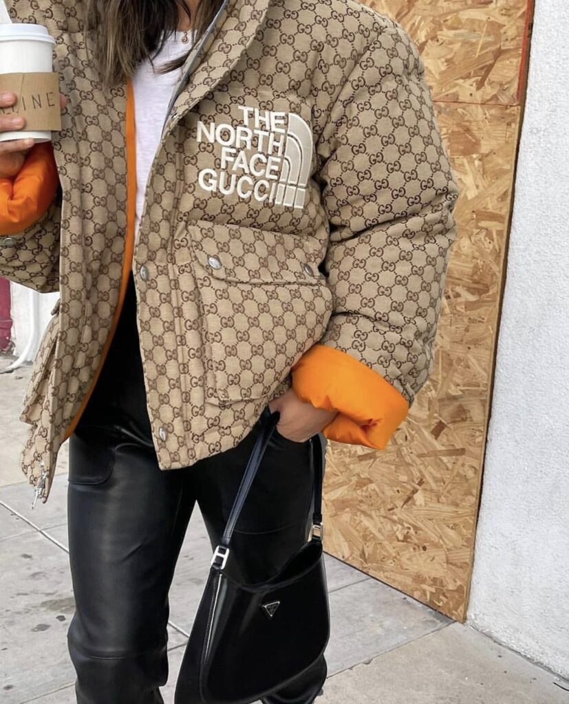Aimee Song with The North Face x Gucci collection on. The North Face x Gucci collection puffer coat. a girl posing with a black purse. a girl wearing gucci in street style look. 