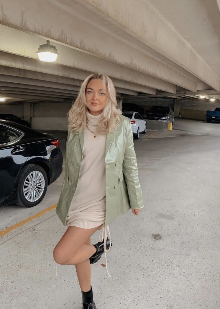 A girl posing in a parking lot. A fashion influencer. A girl with a leather blazer on. Sage Green is going to be a must have color in the spring season.